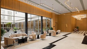 Un hall d’entrée spacieux au design moderne, doté d’un grand espace salon, d’un lustre et de grandes fenêtres.
