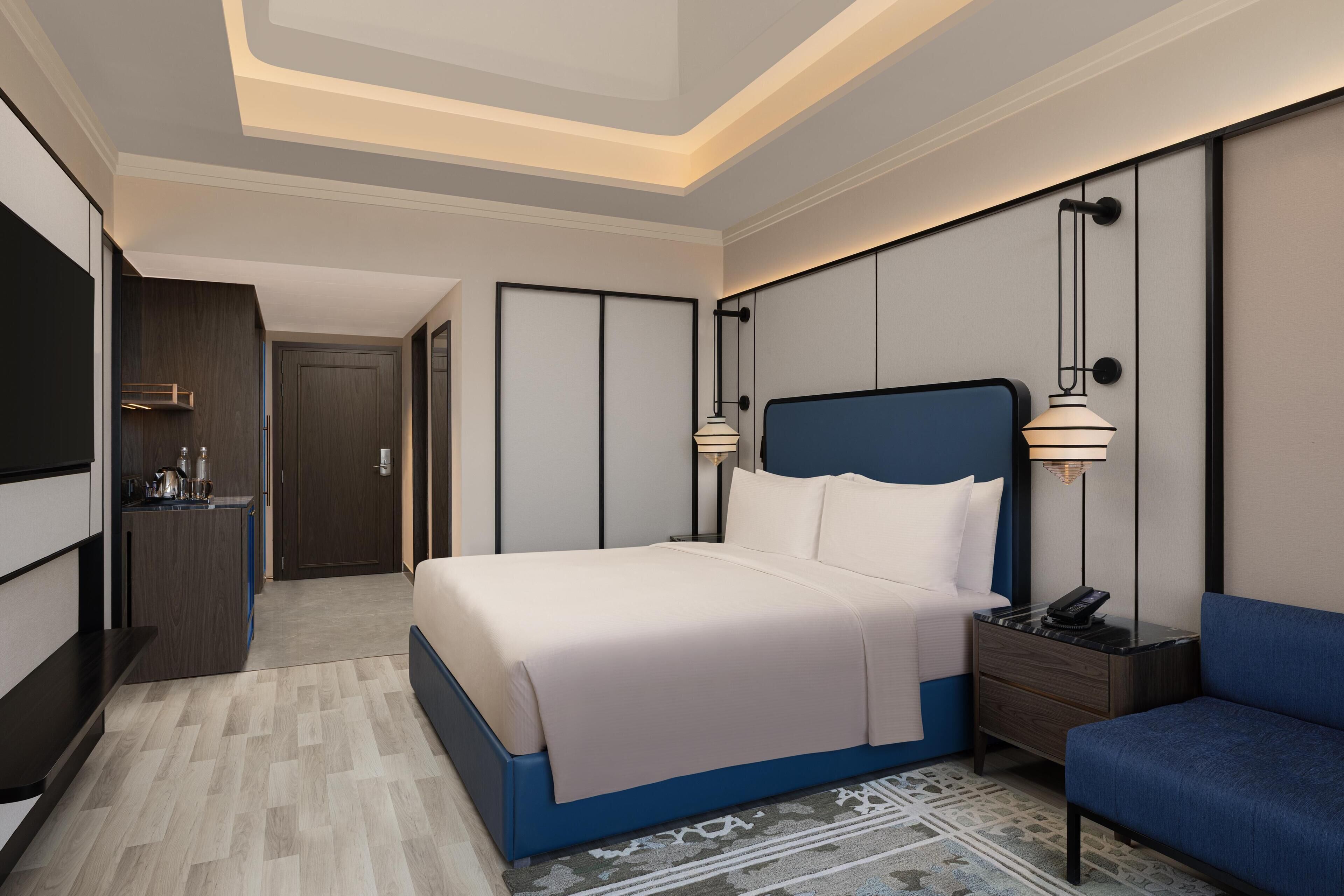 Una habitación de hotel con cama, mesitas de noche, un escritorio, una silla y una televisión.
