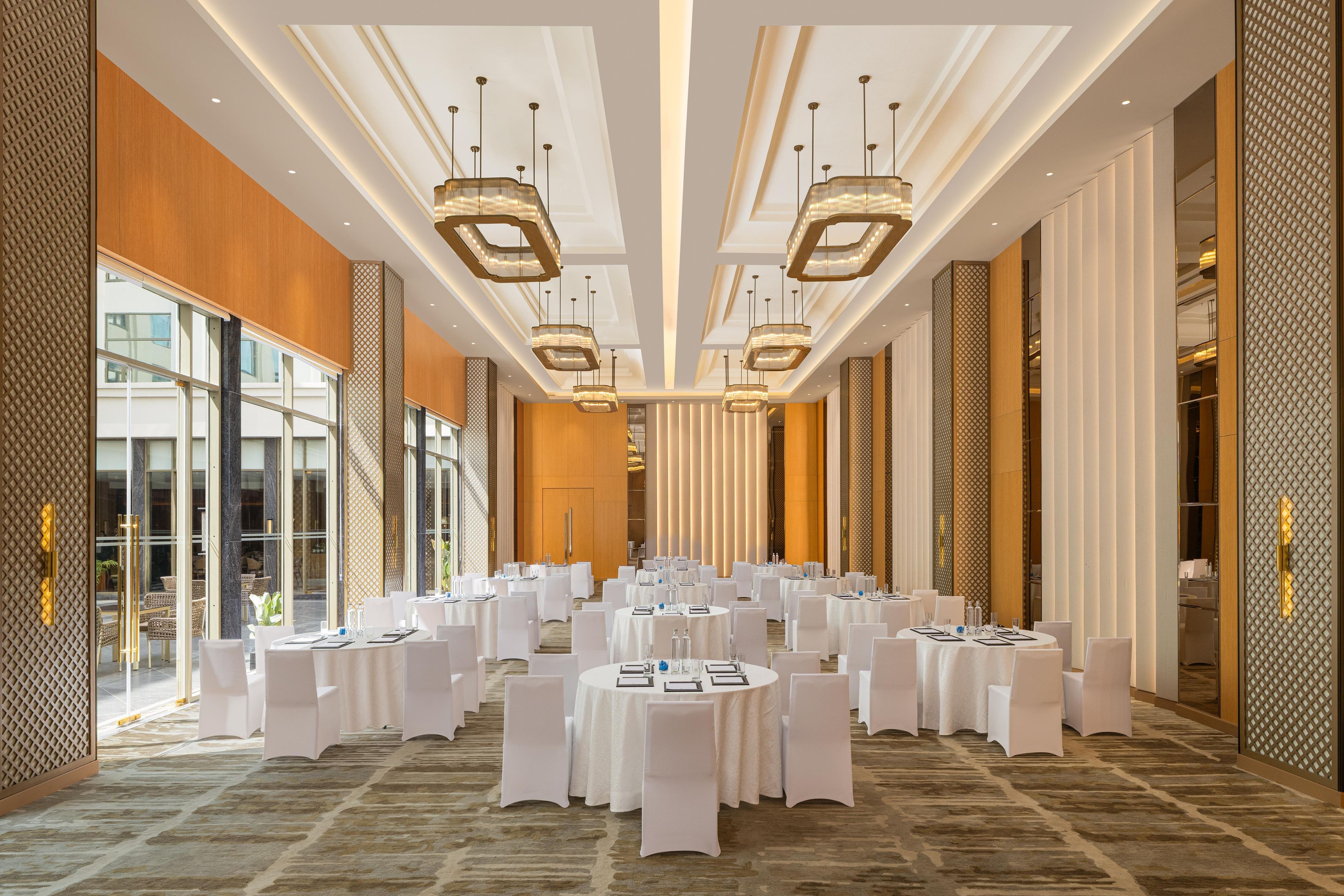 Un amplio salón de banquetes con mesas redondas, manteles blancos y modernos candelabros.