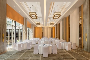 A spacious banquet hall with round tables, white tablecloths, and modern chandeliers. - Doubletree by Hilton Bengaluru Airport (Bengaluru)