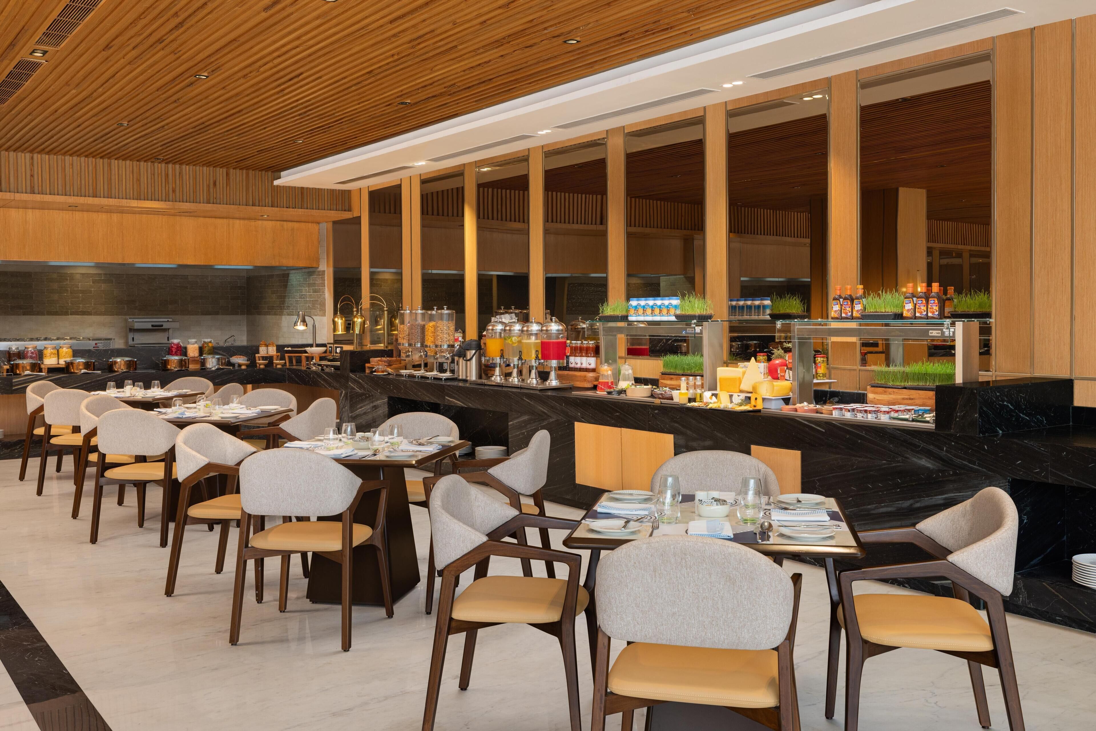 A restaurant with a long counter, multiple tables, and chairs.