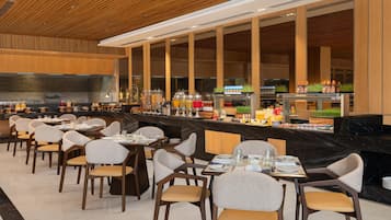 A restaurant with a long counter, multiple tables, and chairs.
