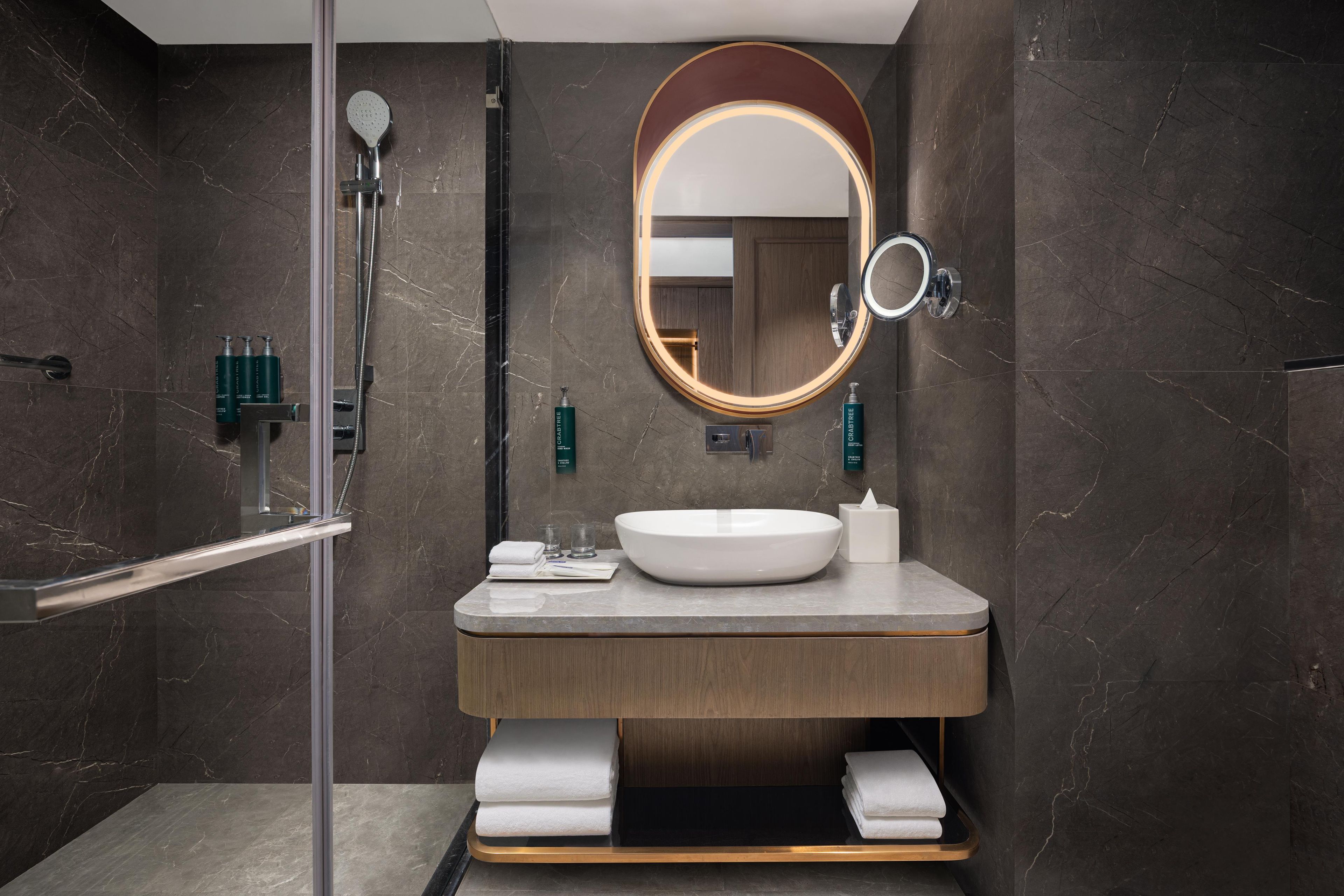 Une salle de bain moderne avec un grand miroir, un lavabo et une douche.