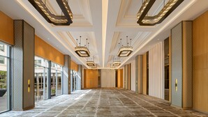 Un vaste couloir aux murs décorés de motifs, doté de grandes fenêtres et d’un éclairage moderne.