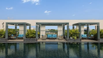 A pool area with three covered seating areas, each with a bench and a chair.