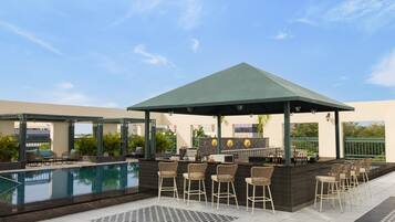 A rooftop pool area with a bar and seating.