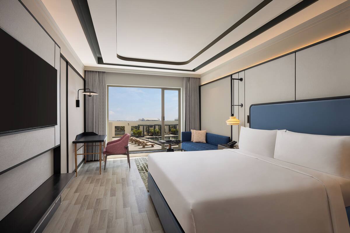 Een moderne hotelkamer met een groot bed, een bureau, een stoel en uitzicht op de omgeving.