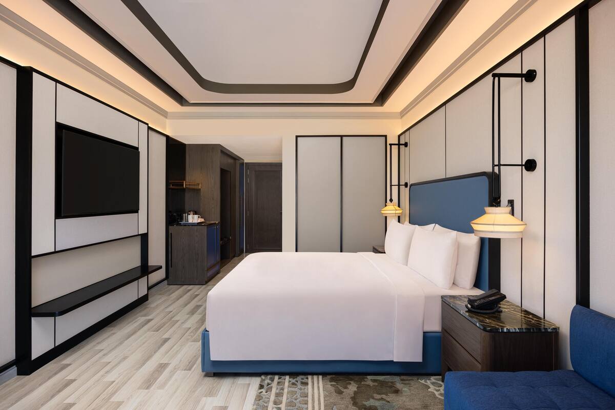 Een moderne hotelkamer met een groot bed, nachtkastjes, een televisie en een werkplek.