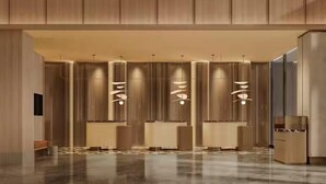 Una hall moderna con una reception centrale, lampade a sospensione verticali e un pavimento lucido.