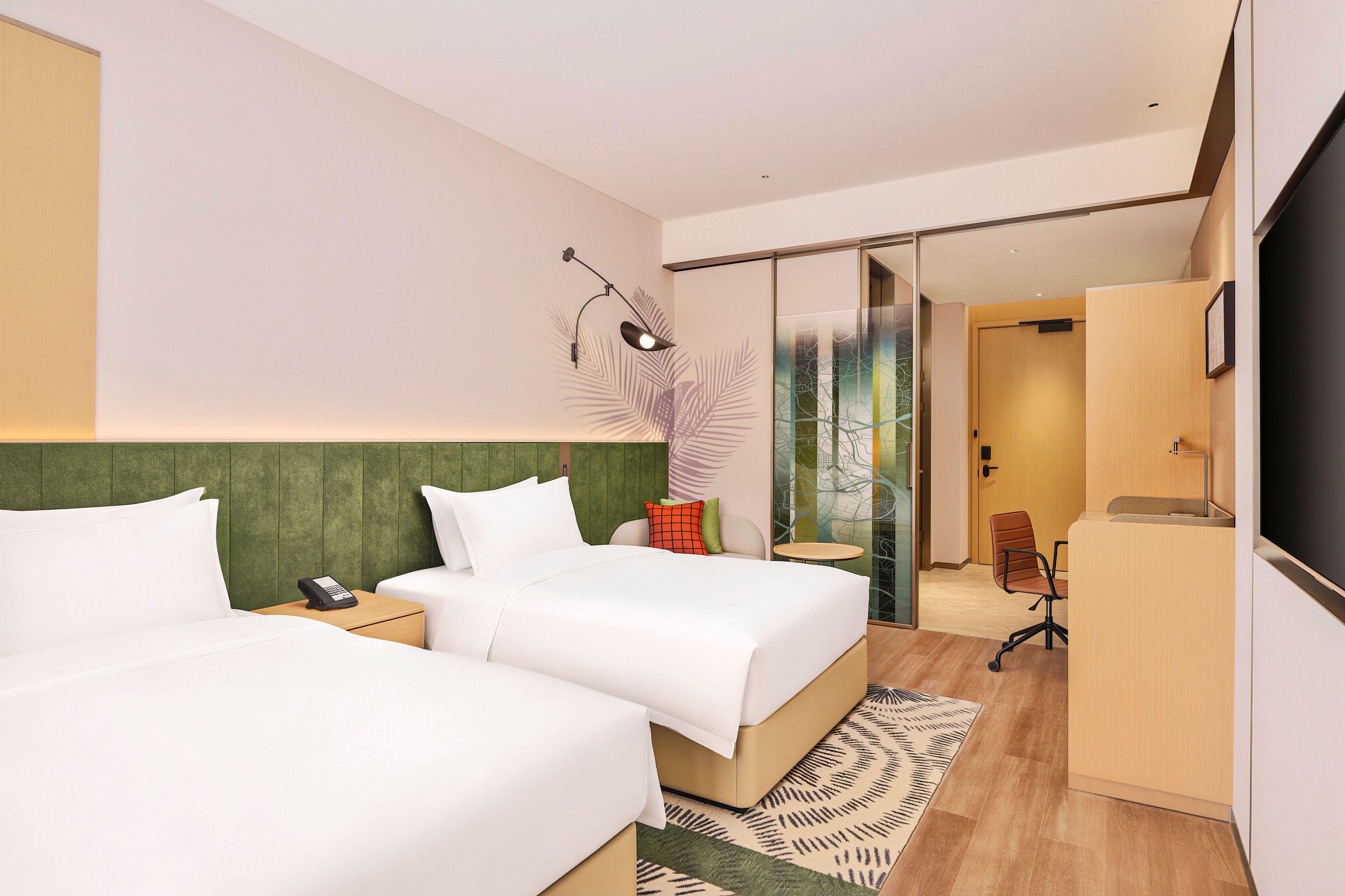 Une chambre d’hôtel avec deux lits, un bureau, une chaise, une télévision et une porte vitrée donnant sur une salle de bain.