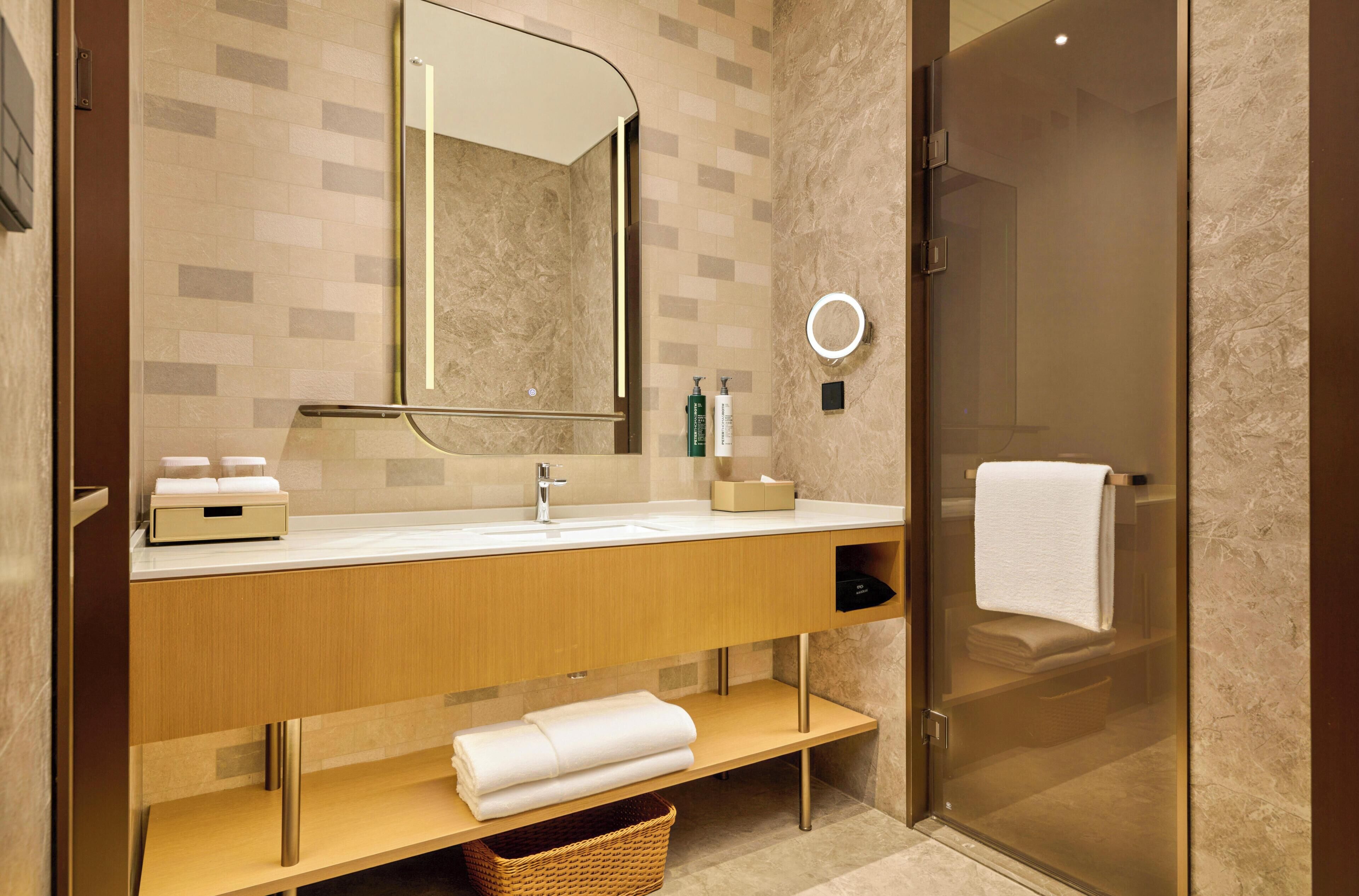 A modern bathroom with a glass shower enclosure, a wooden vanity with a mirror, and a towel rack.