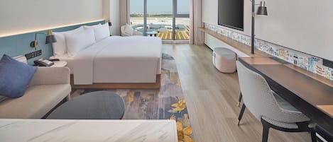 Una habitación de hotel moderna con una cama grande, un sofá, un escritorio y un televisor.
