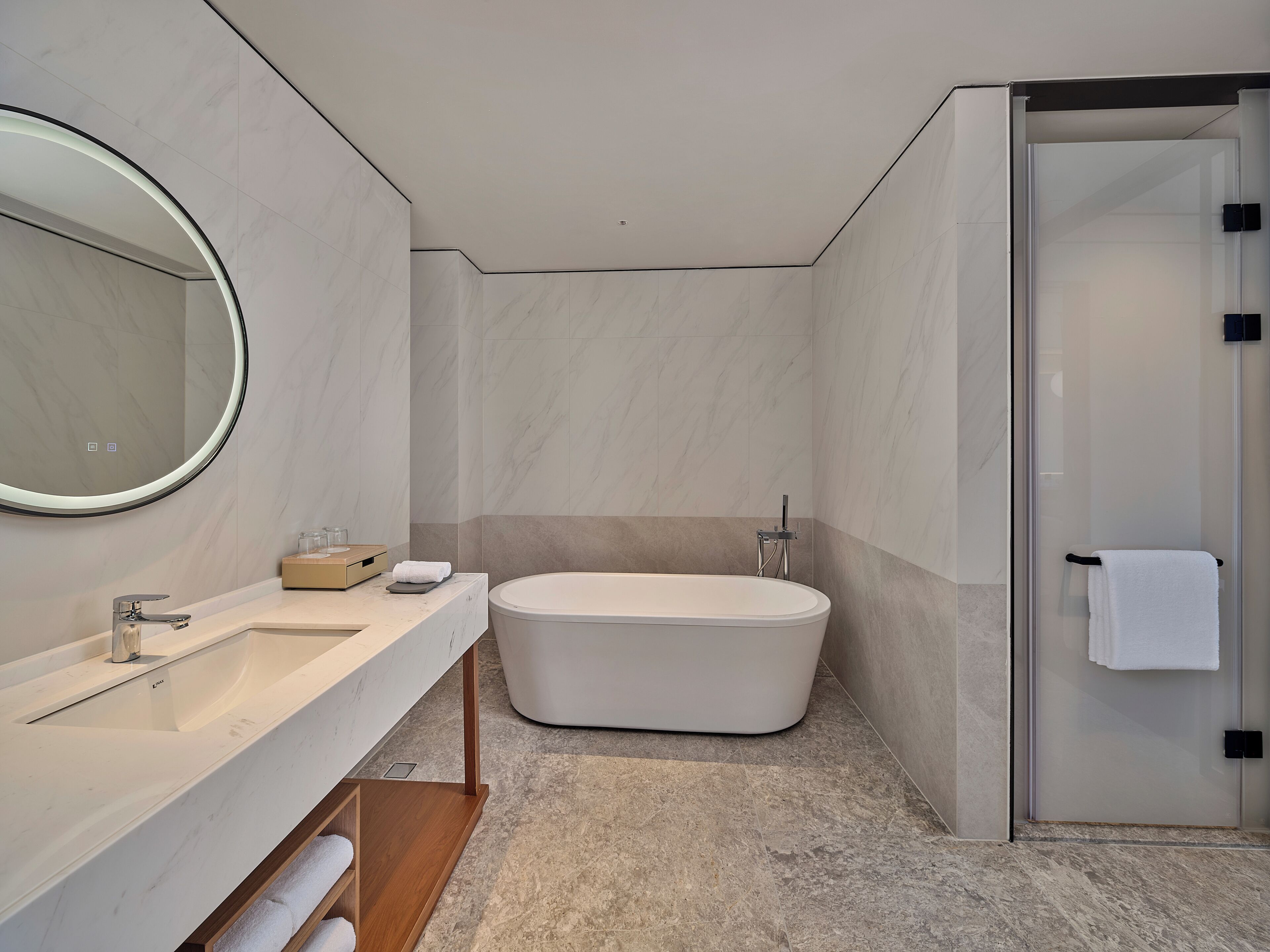 A modern bathroom with a freestanding bathtub, a large mirror, and a glass-enclosed shower.