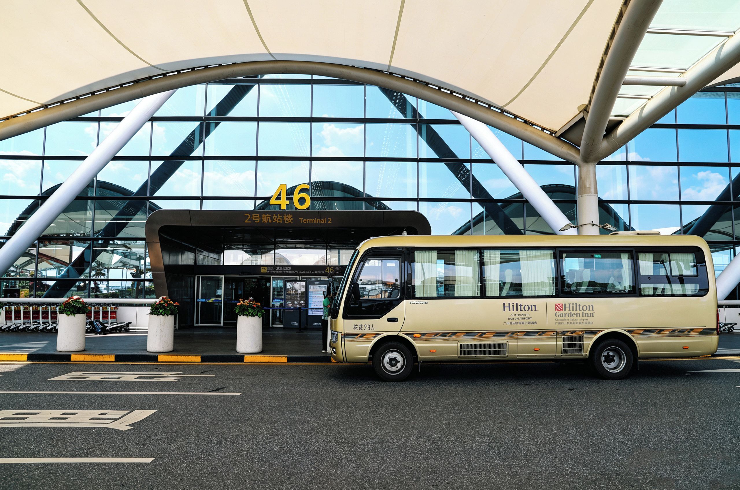 A bus parked in front of a modern building with a large glass facade and a curved roof structure.