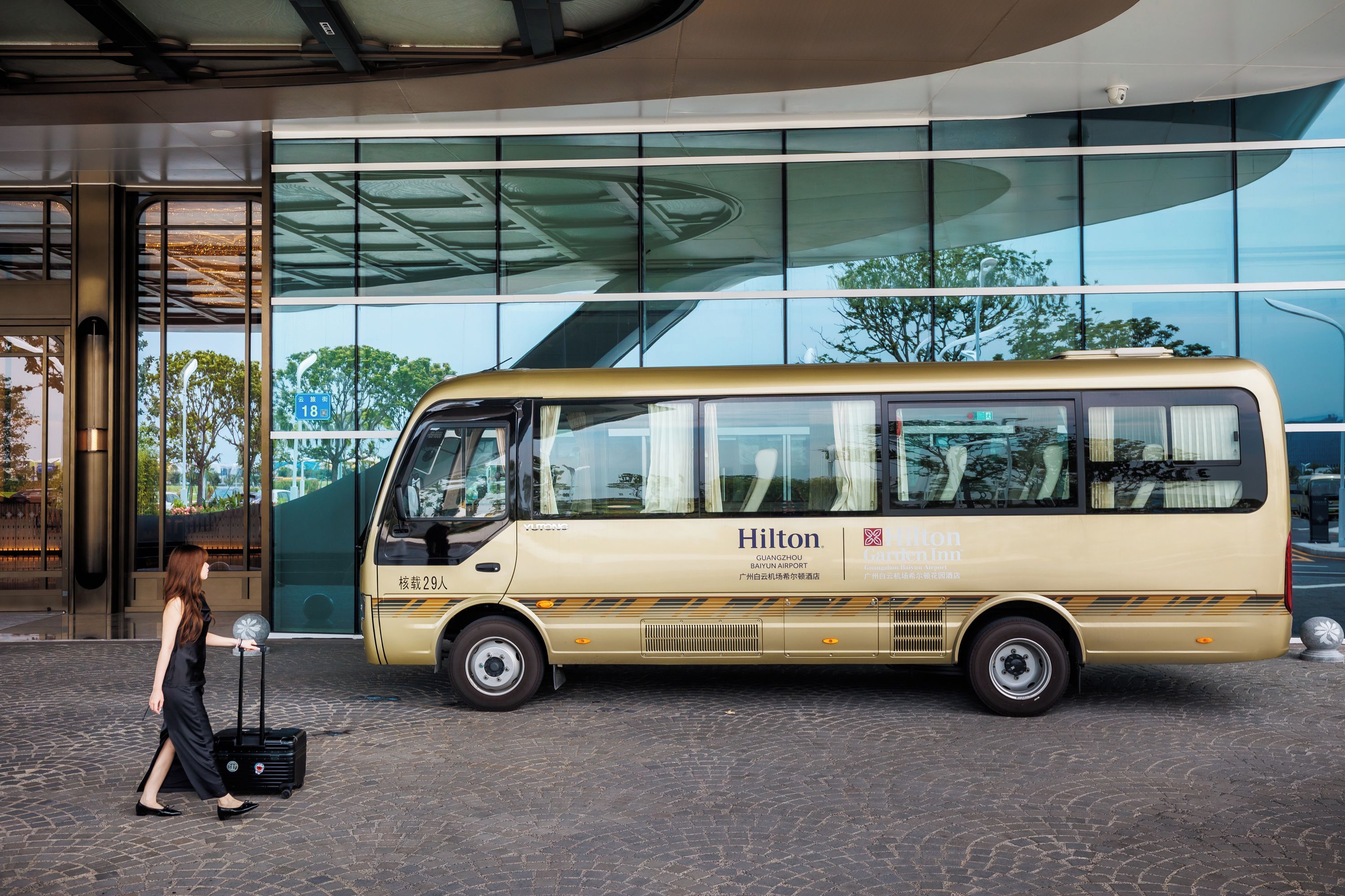 A bus parked in front of a building with large windows and a curved roof.
