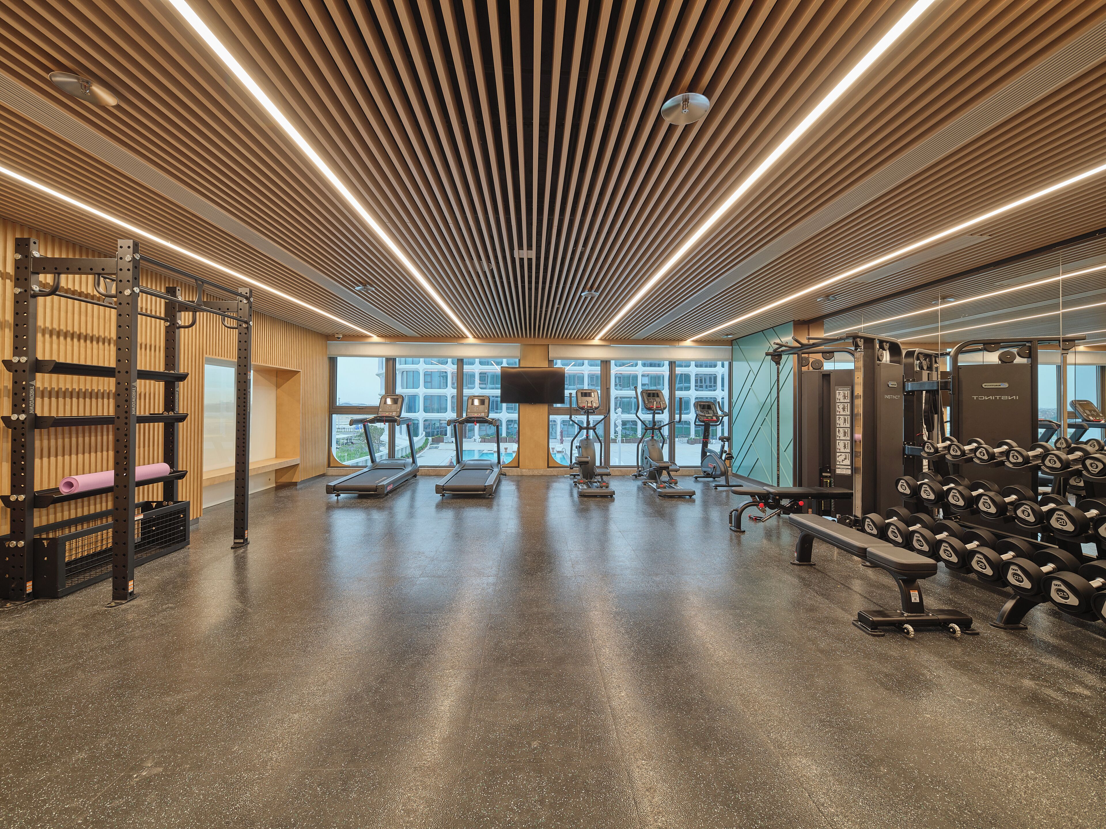 Une salle de sport équipée de tapis de course, de vélos elliptiques et d’appareils de musculation.