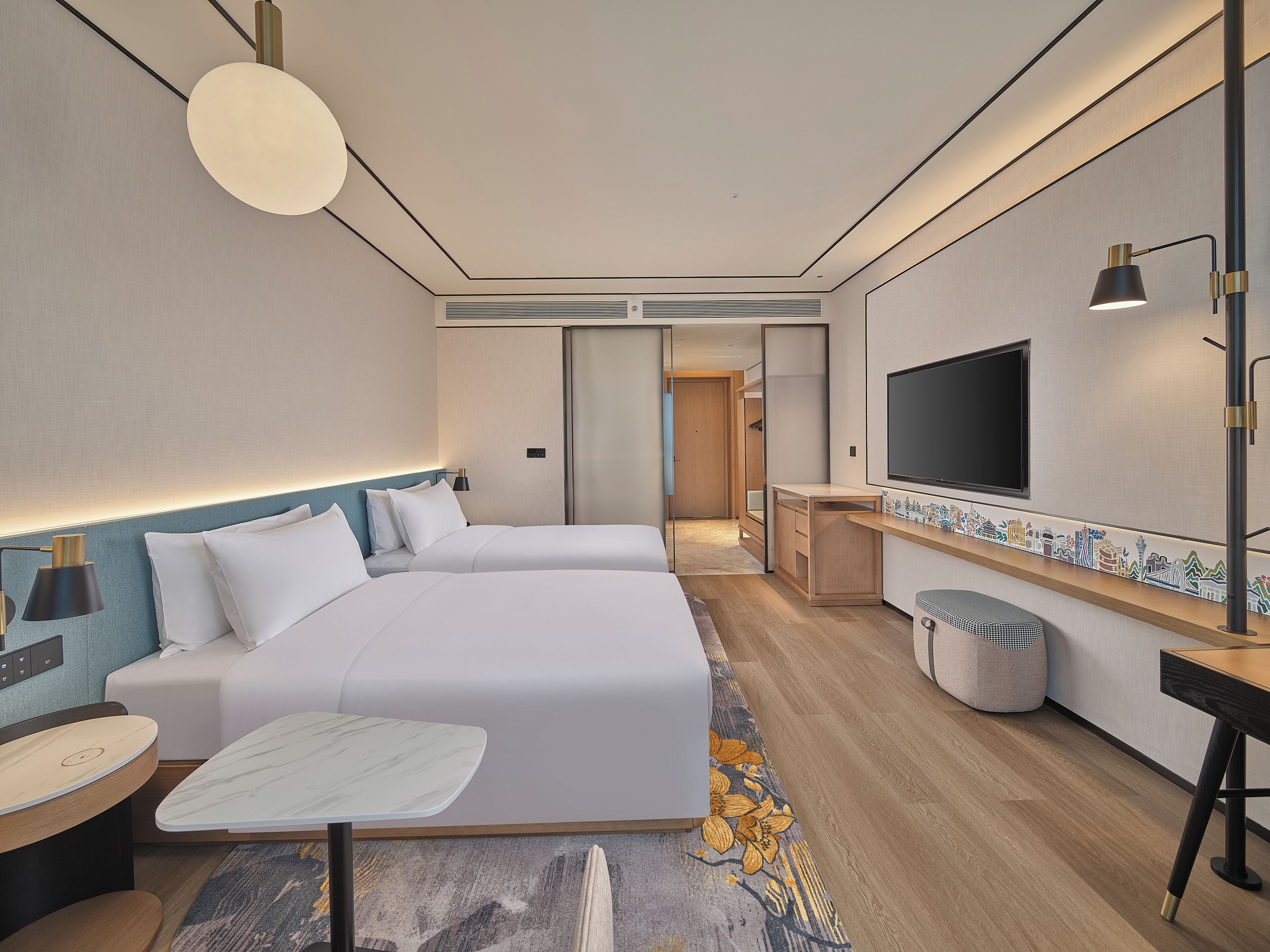 A modern hotel room with a large bed, a desk, a TV, and a seating area.