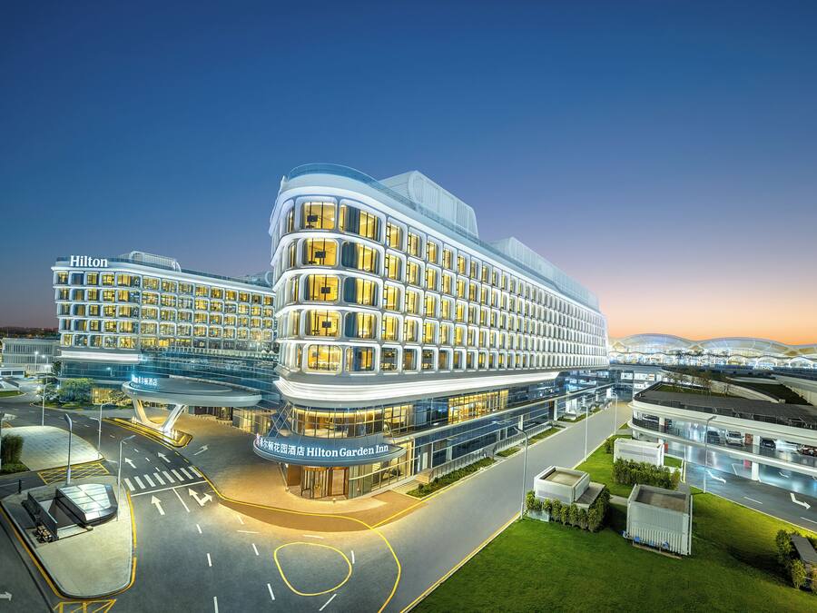 A multi-story hotel with a modern design, featuring a prominent entrance and a well-lit facade.