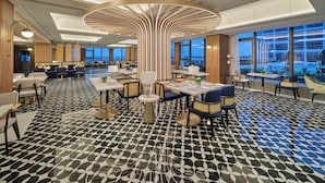 A spacious hotel lobby with a modern design, featuring a central light fixture, multiple seating areas, and large windows offering city views. - Hilton Garden Inn Guangzhou Baiyun Airport Terminal 3 (Guangzhou)