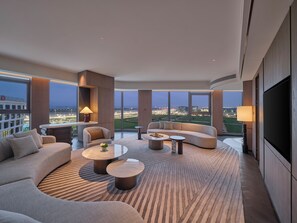 A modern hotel room with a large sofa, a smaller sofa, two round coffee tables, a TV, and a view of a cityscape. - Hilton Guangzhou Baiyun Airport Terminal 3 (Guangzhou)