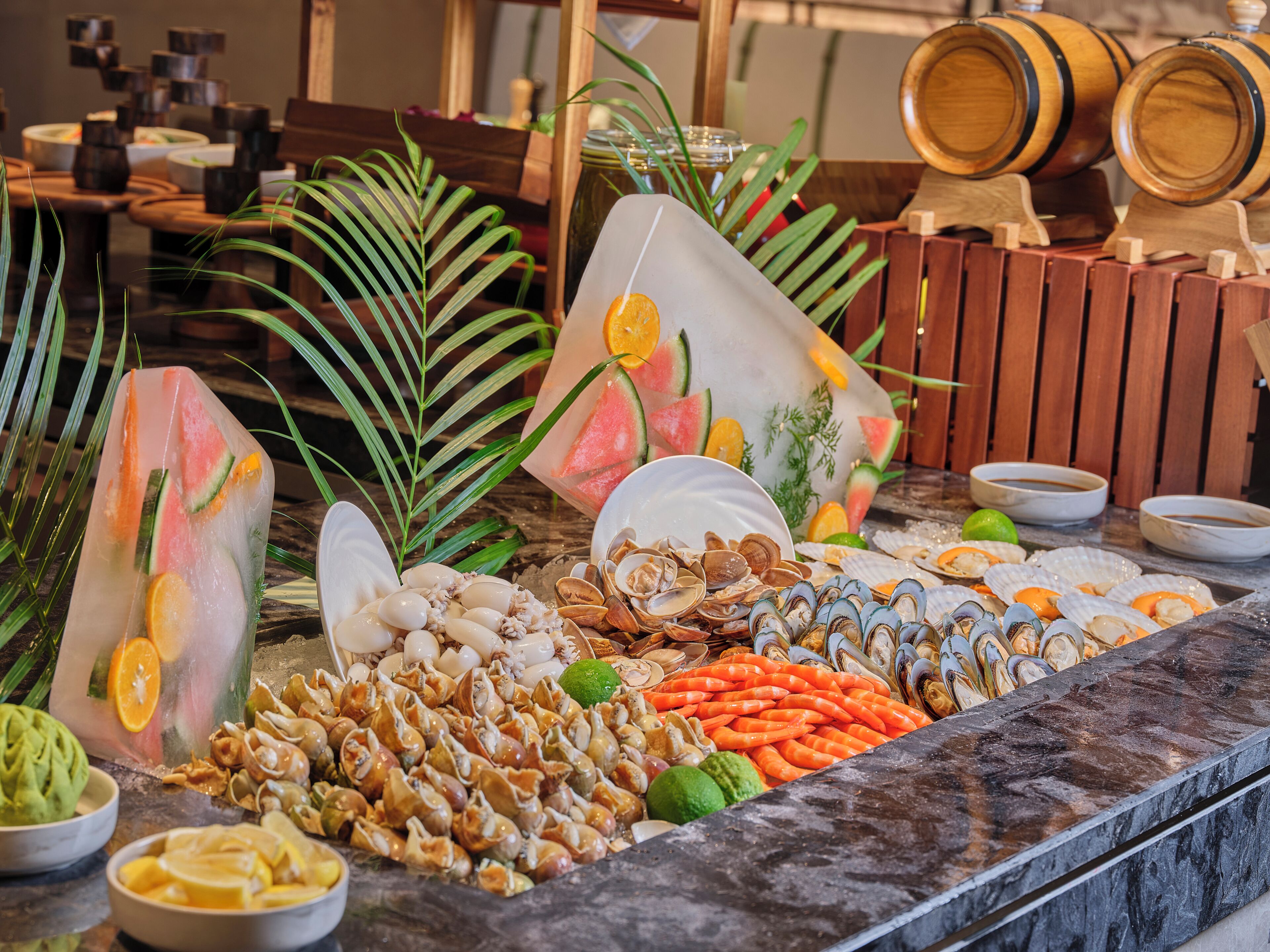 A buffet with seafood, fruits, and a decorative ice sculpture.