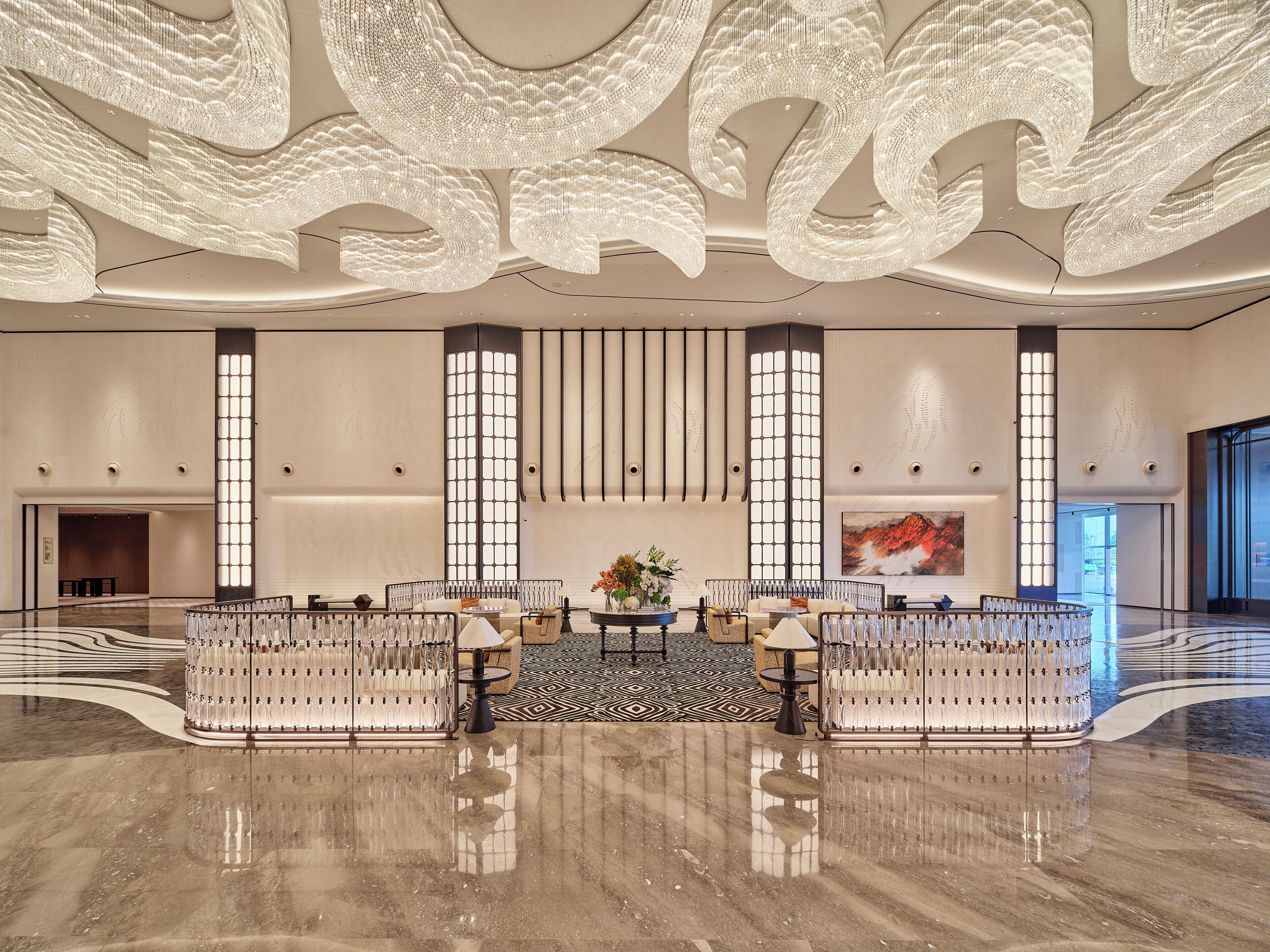 A spacious lobby with a high ceiling, a central seating area, and a large wall-mounted television.
