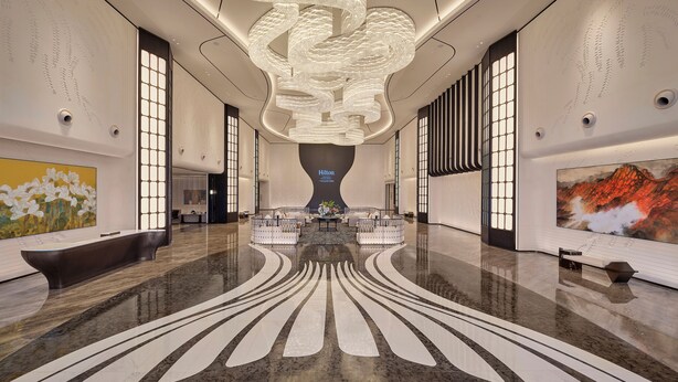 A spacious lobby with a central seating area, a large chandelier, and artwork on the walls. - Hilton Guangzhou Baiyun Airport Terminal 3 (Guangzhou)