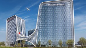 A modern hotel with a distinctive curved facade and a clear sky. - Doubletree By Hilton Zhengzhou Airport Aerotropolis (Zhengzhou)