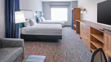 Une chambre d’hôtel avec deux lits, un bureau, une chaise, une télévision et un canapé.