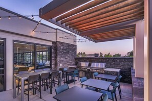 En udendørs terrasse med stenvæg, grillområde og siddepladser.