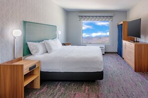 A hotel room with a bed, a TV, a desk, and a window with a mountain view. - Home2 Suites By Hilton Carson City (Carson City)