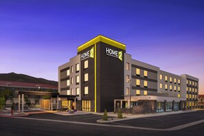 A multi-story hotel with a modern design, featuring a prominent 'HOME 2' sign, a covered outdoor seating area, and a parking lot. - Home2 Suites By Hilton Carson City (Carson City)