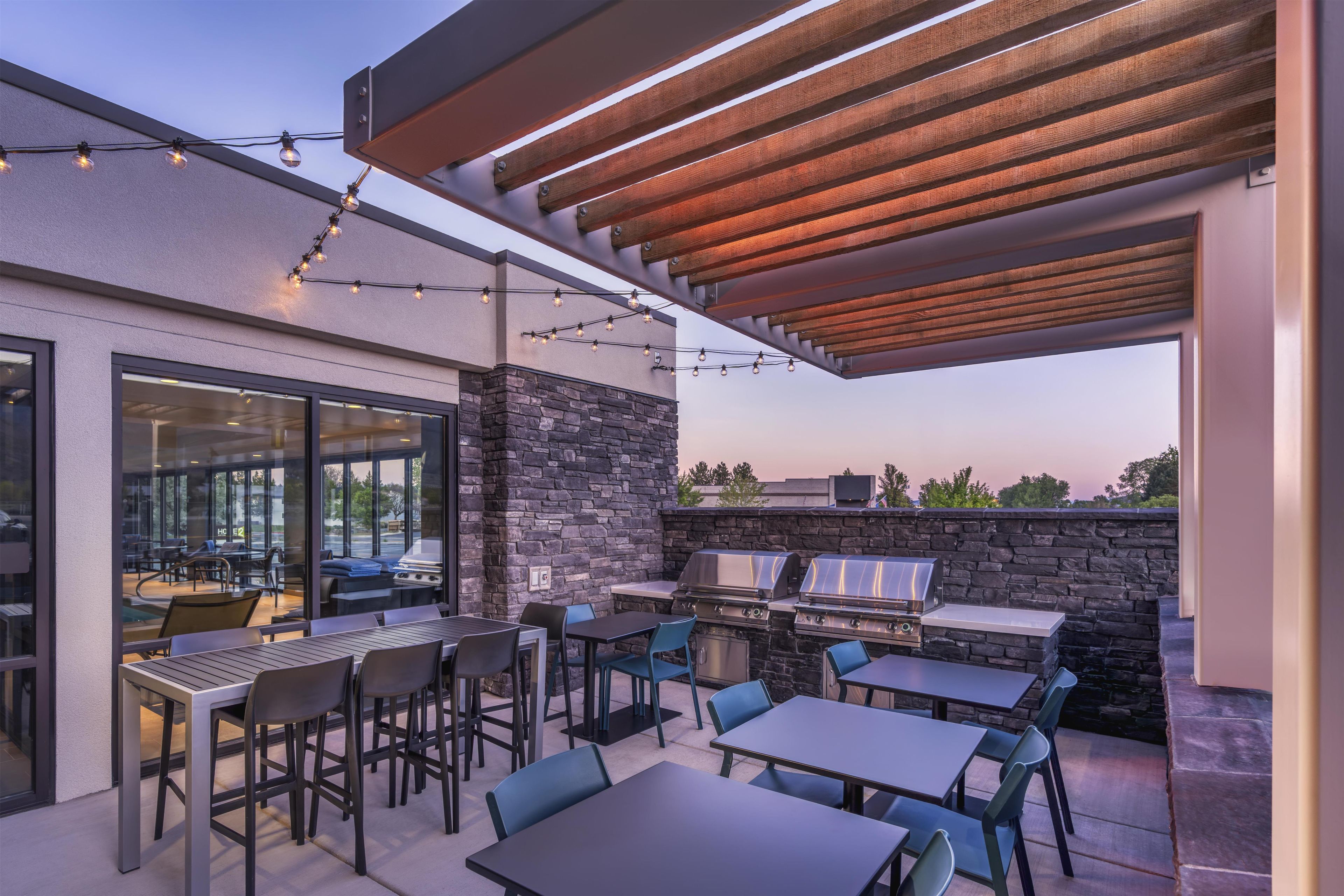 An outdoor patio with a stone wall, grilling area, and seating.
