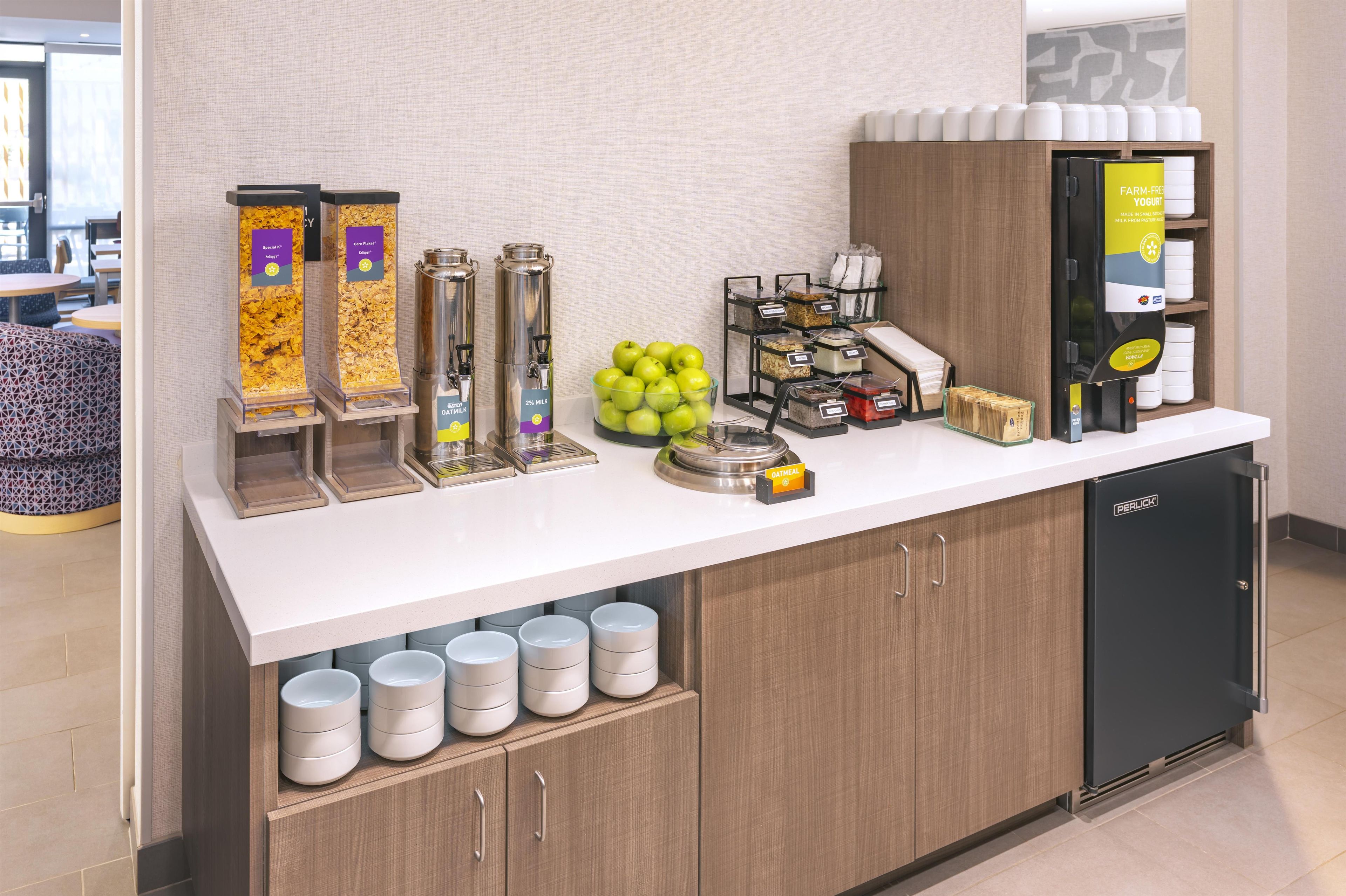Zona de petit esmorzar amb dispensadors de cafè, un plat de fruita i un frigorífic.