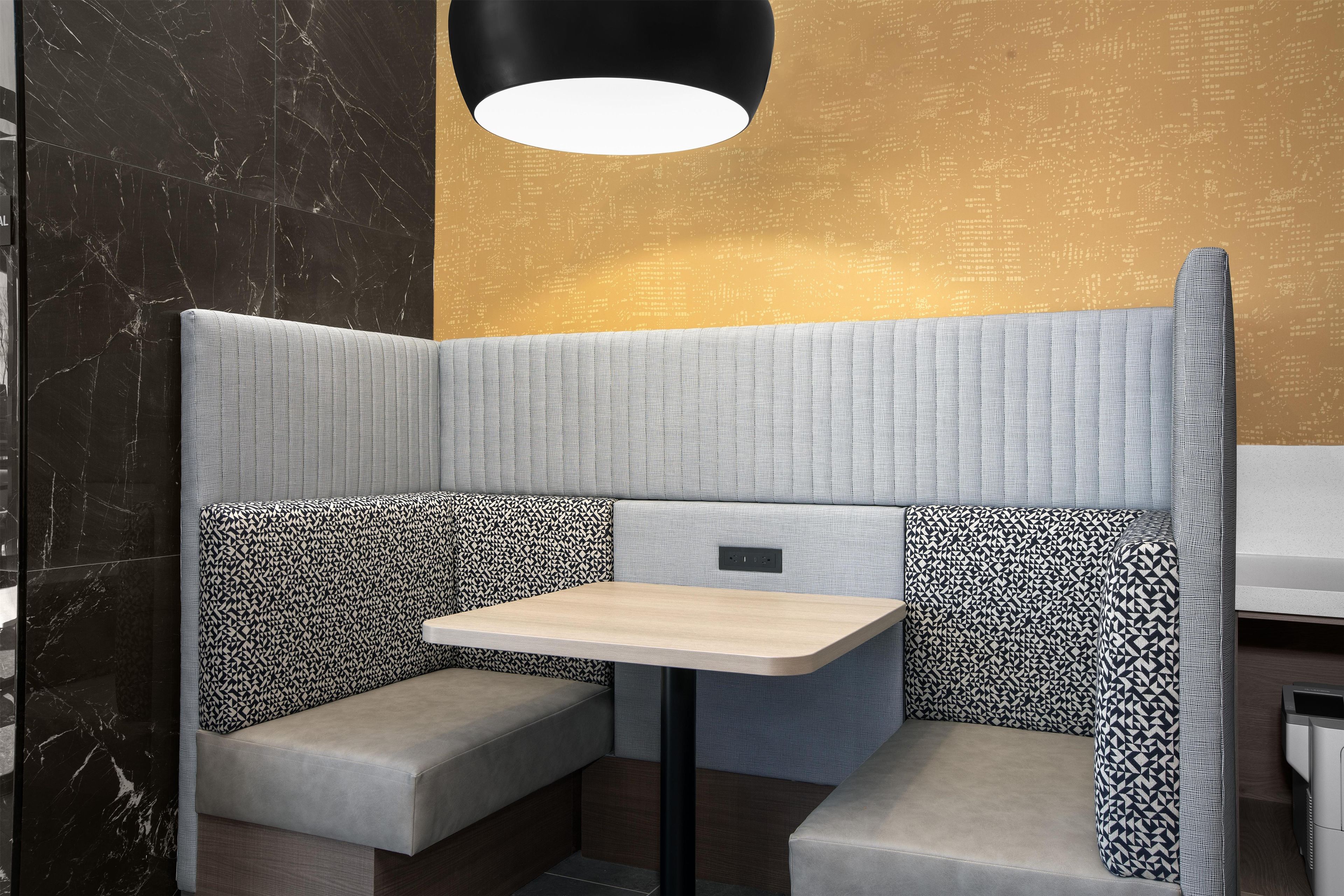 A corner seating area with a table, cushioned benches, and a patterned wall.