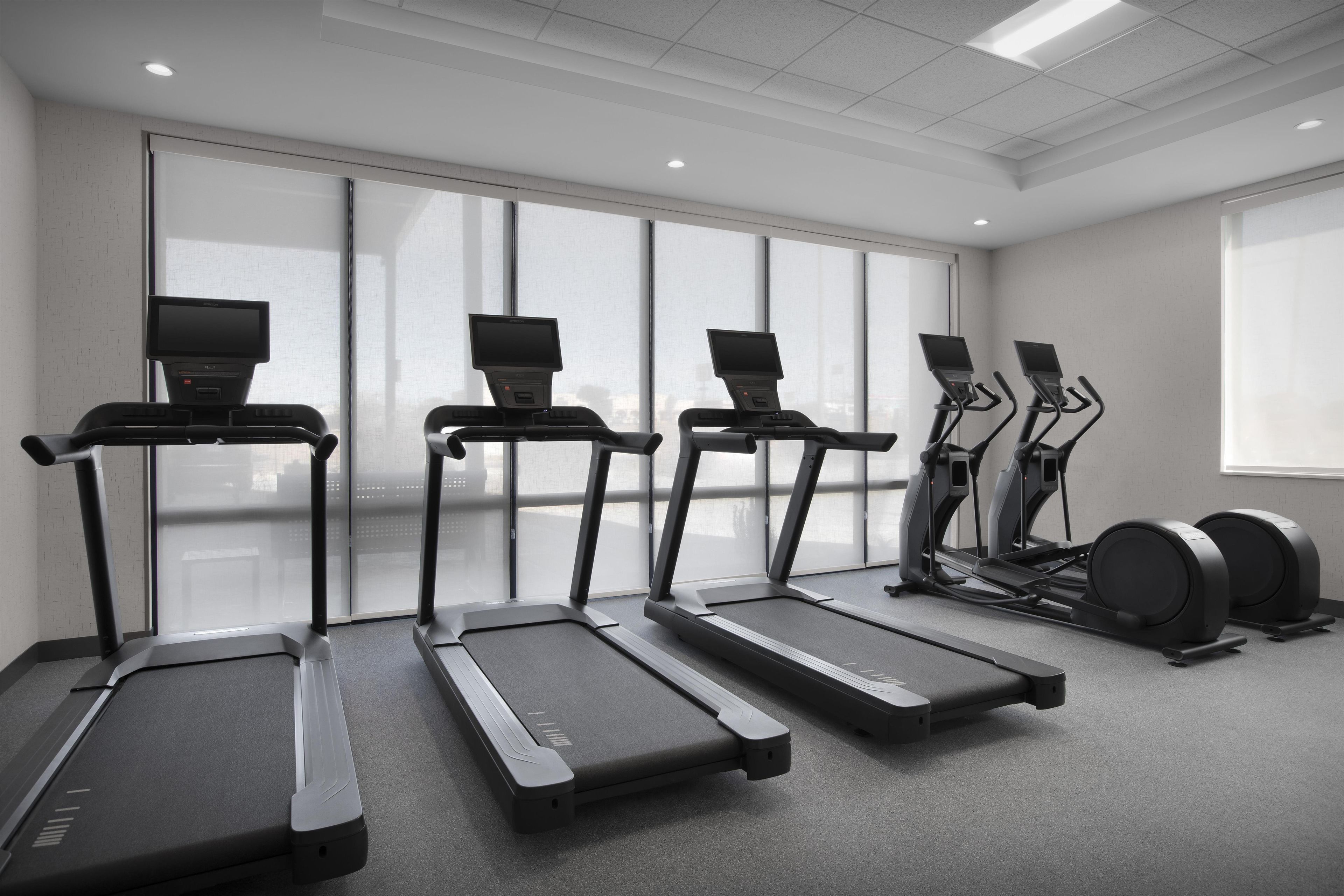 A gym with four treadmills, two elliptical machines, and a set of dumbbells.