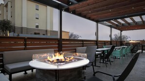 An outdoor patio with a fire pit, seating, and tables.