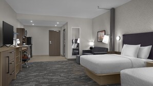 A hotel room with a bed, a desk, a chair, a TV, and a mirror.