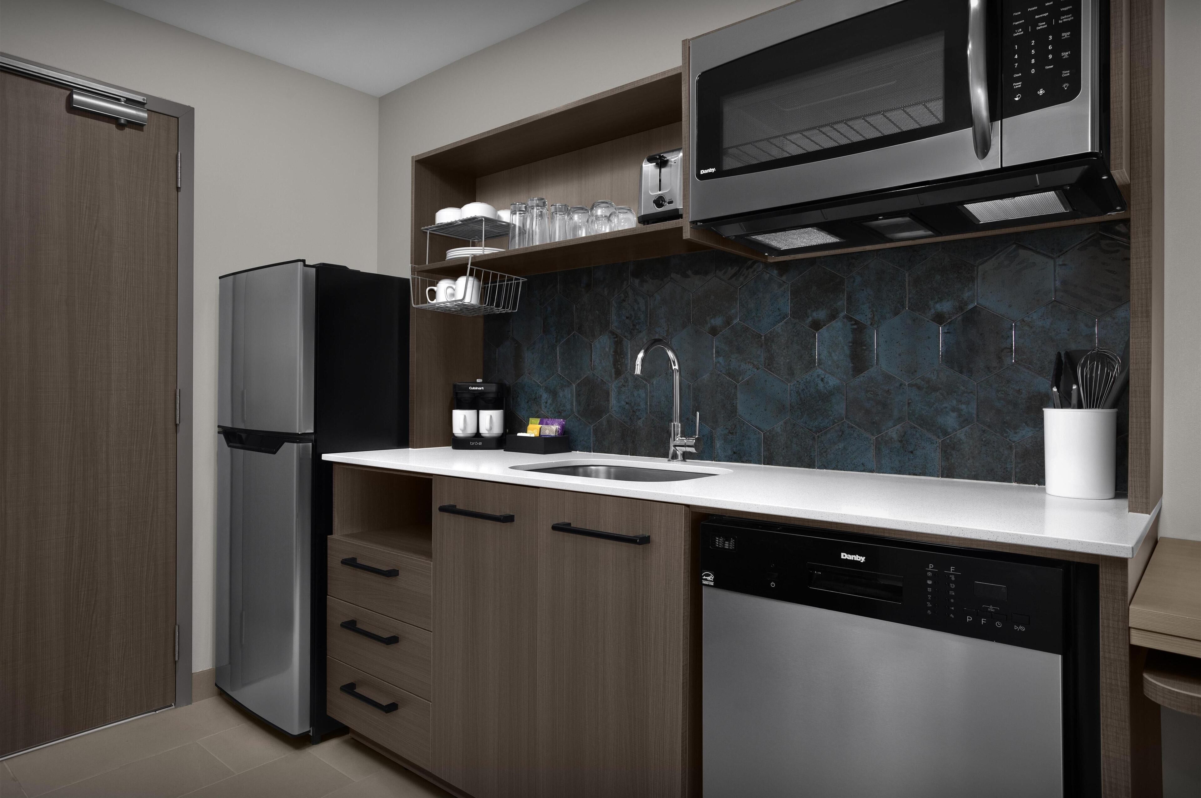 A modern kitchen with a stainless steel refrigerator, a microwave, a dishwasher, and a sink with a faucet.
