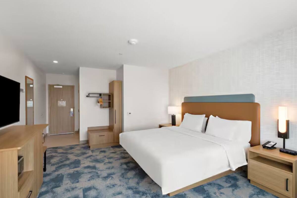 Een hotelkamer met een bed, nachtkastjes, een televisie en een kledingkast.