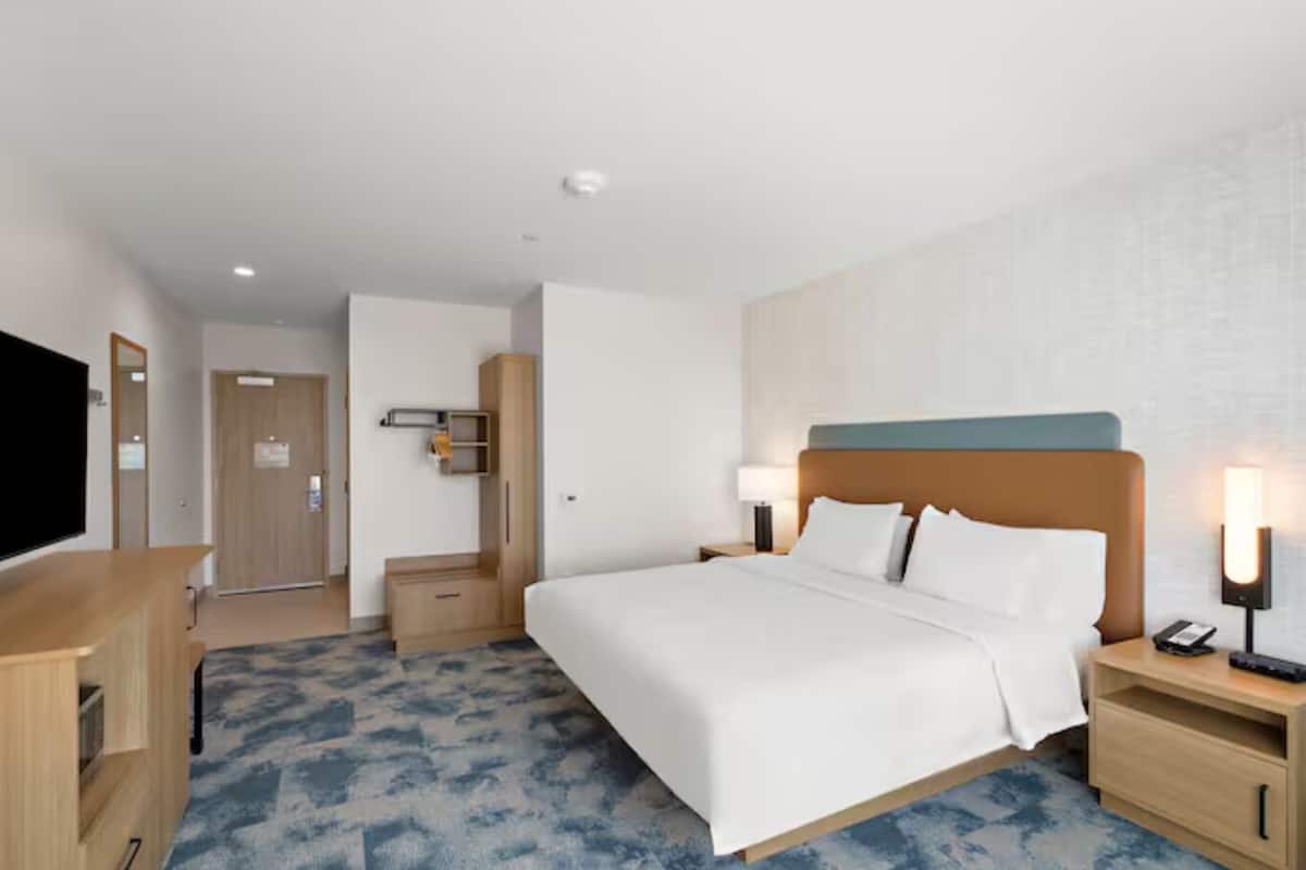 A hotel room with a bed, bedside tables, a TV, and a wardrobe.