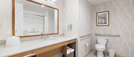 A modern bathroom with a large mirror, a sink, a toilet, and a shower area.
