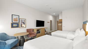 Une chambre d’hôtel avec deux lits, un bureau doté d’un téléviseur à écran plat, une chaise, une petite table et un téléviseur fixé au mur.