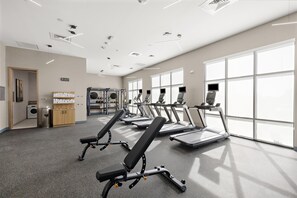 A gym with treadmills, weight machines, and a large window. - Hampton Inn By Hilton Ontario Airport (Ontario)