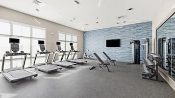 Une salle de sport équipée de tapis de course, de bancs de musculation et d’autres appareils d’exercice.