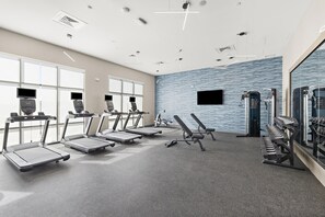 Une salle de sport équipée de tapis de course, de bancs de musculation et d’autres appareils d’exercice.
