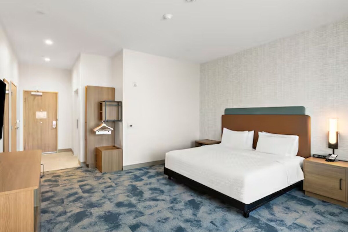 Une chambre d’hôtel comprenant un lit, des tables de chevet, une télévision, une armoire et un miroir.