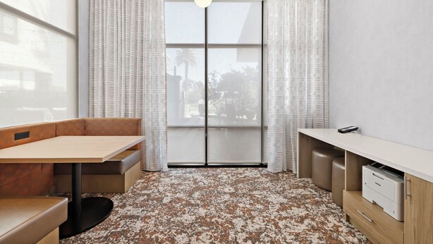 A modern room with a sofa, a table, a desk, a printer, and a large window with curtains. - Hampton Inn By Hilton Ontario Airport (Ontario)