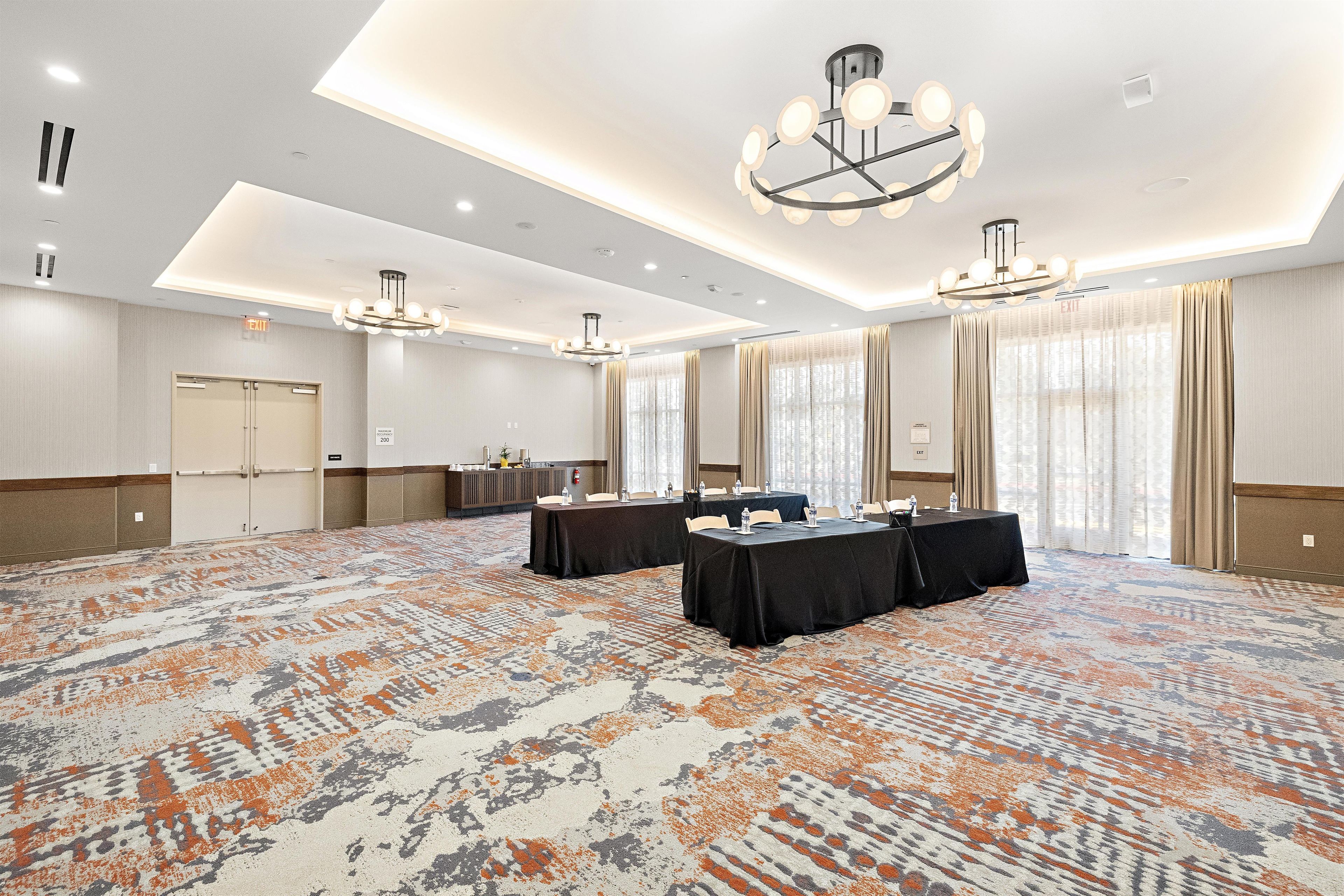 Une salle de conférence équipée de tables, de chaises et d’un tapis à motifs.