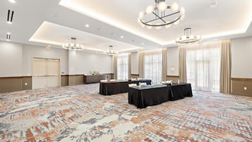 Une salle de conférence équipée de tables, de chaises et d’un tapis à motifs.
